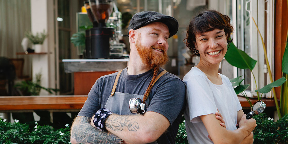 Two employees standing in front of their coffee shop